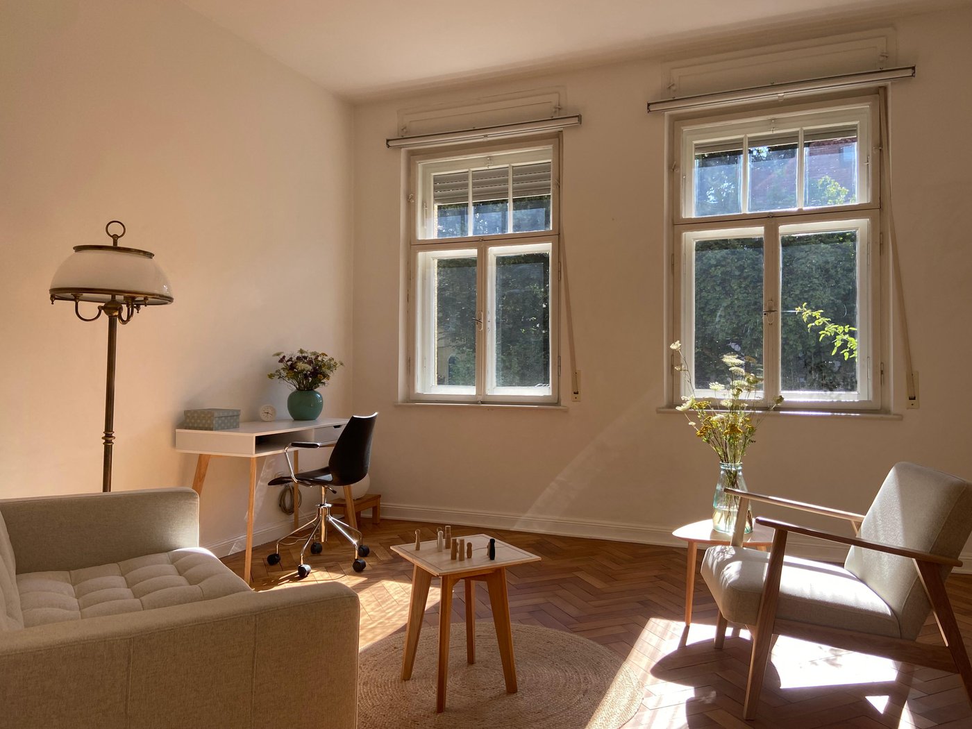 Praxisraum mit Sofa, Sesseln und Systembrett im warmen Sonnenlicht