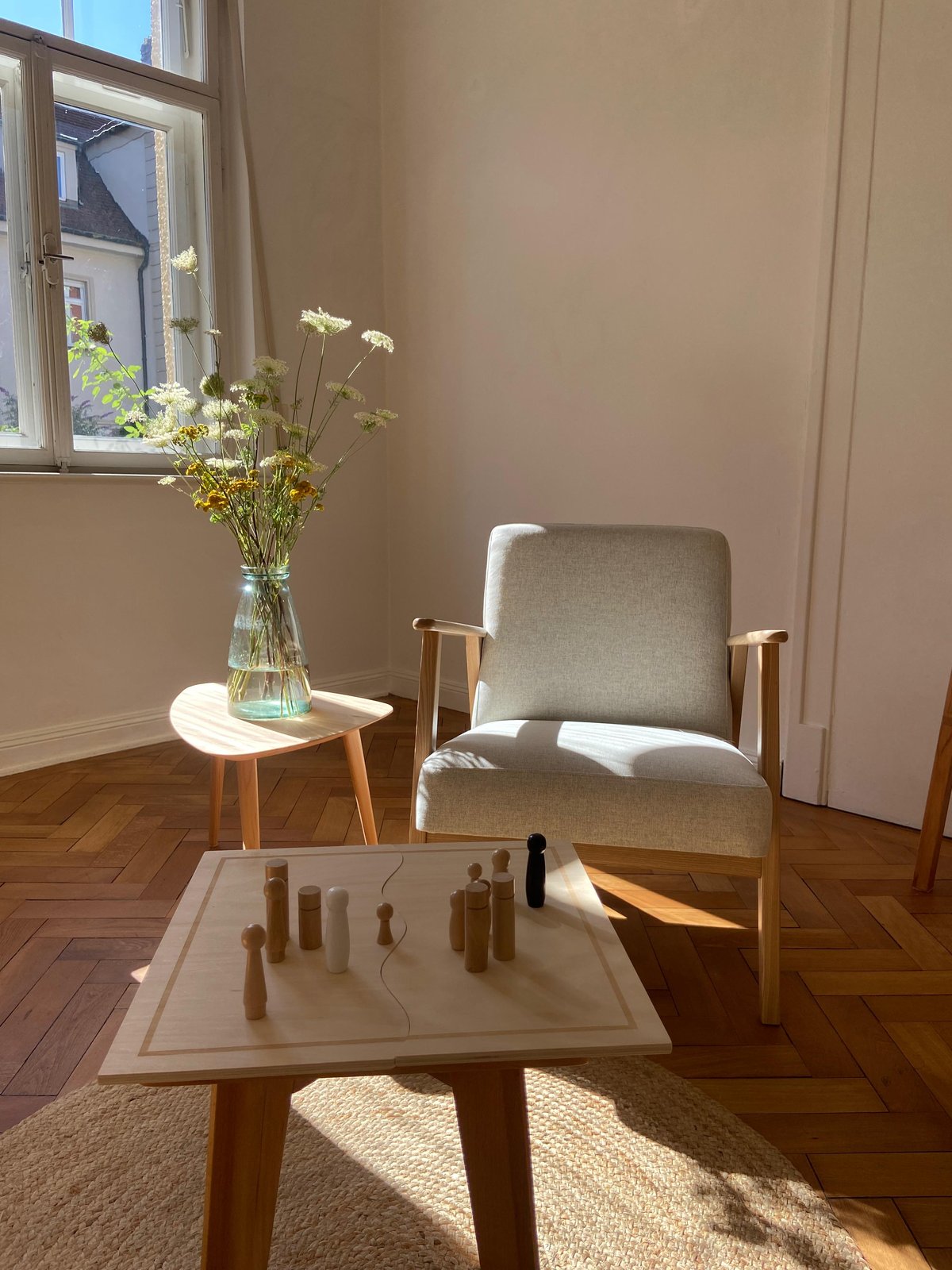 Heller Praxisraum mit Sessel, Blumen und Systembrett mit Aufstellungsfiguren